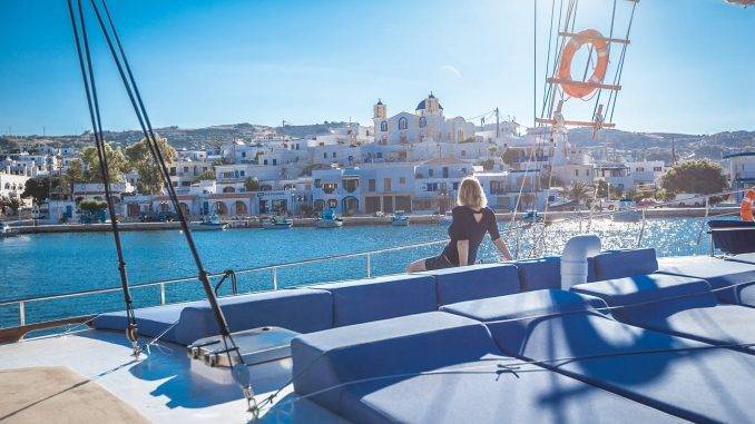 Femme sur le pont d'un bateau admirant la vue sur une île grecque