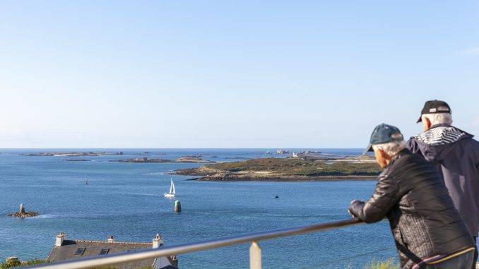 Seniors accoudés à une balustrade en train de contempler un paysage marin breton